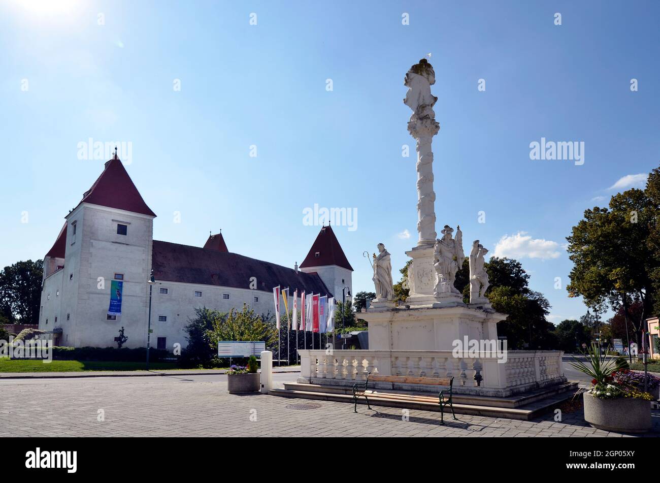 Orth an der Donau, Austria - 04 de septiembre de 2021: Columna de la Santísima Trinidad y Orth castillo en la Baja Austria, antiguo castillo mudo ahora utilizado como museo y cen Foto de stock