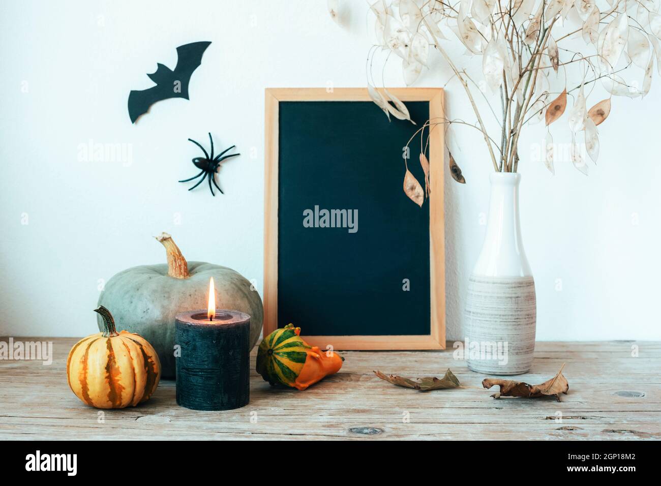 Composición de Halloween con pizarrón, calabazas, velas y flores secas en jarrón, murciélago y araña. Fondo festivo, primeros planos. Espacio de copia. Foto de stock
