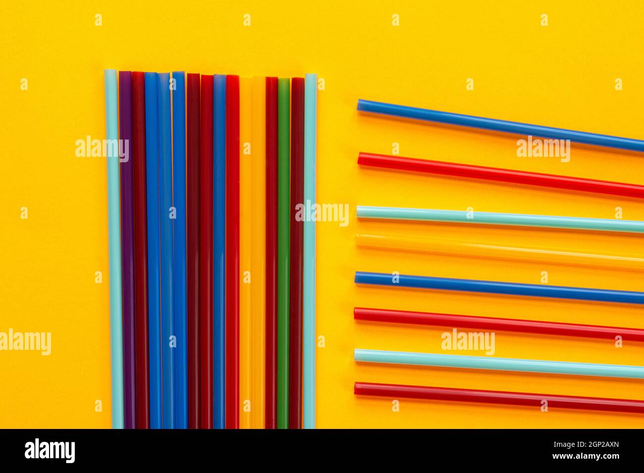 Sobre un fondo amarillo, los tubos de cóctel multicolores yacen, junto a un montón de tubos verticales yacen horizontales Foto de stock