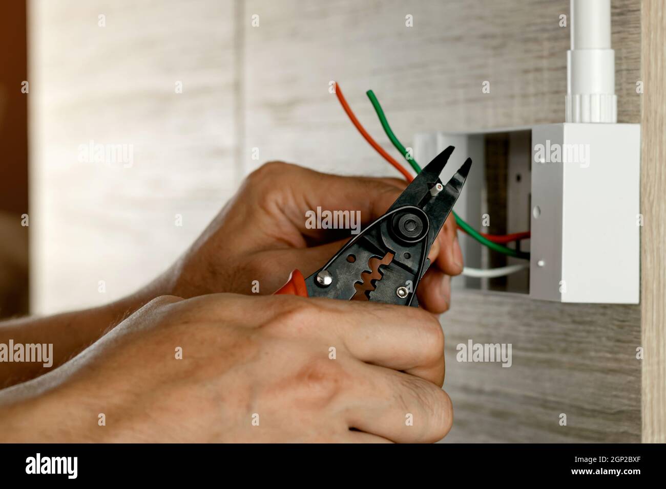 El electricista está pelando los cables eléctricos en una caja de plástico  en una pared de madera para instalar la toma de corriente Fotografía de  stock - Alamy