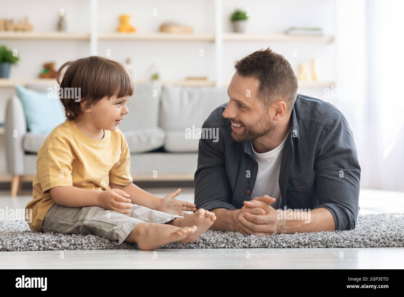 Comunicación entre padre e hijo. Niño pequeño positivo hablando con su  alegre papá, padre de carrng escuchando a su hijo, sentado en el suelo en  casa Fotografía de stock - Alamy