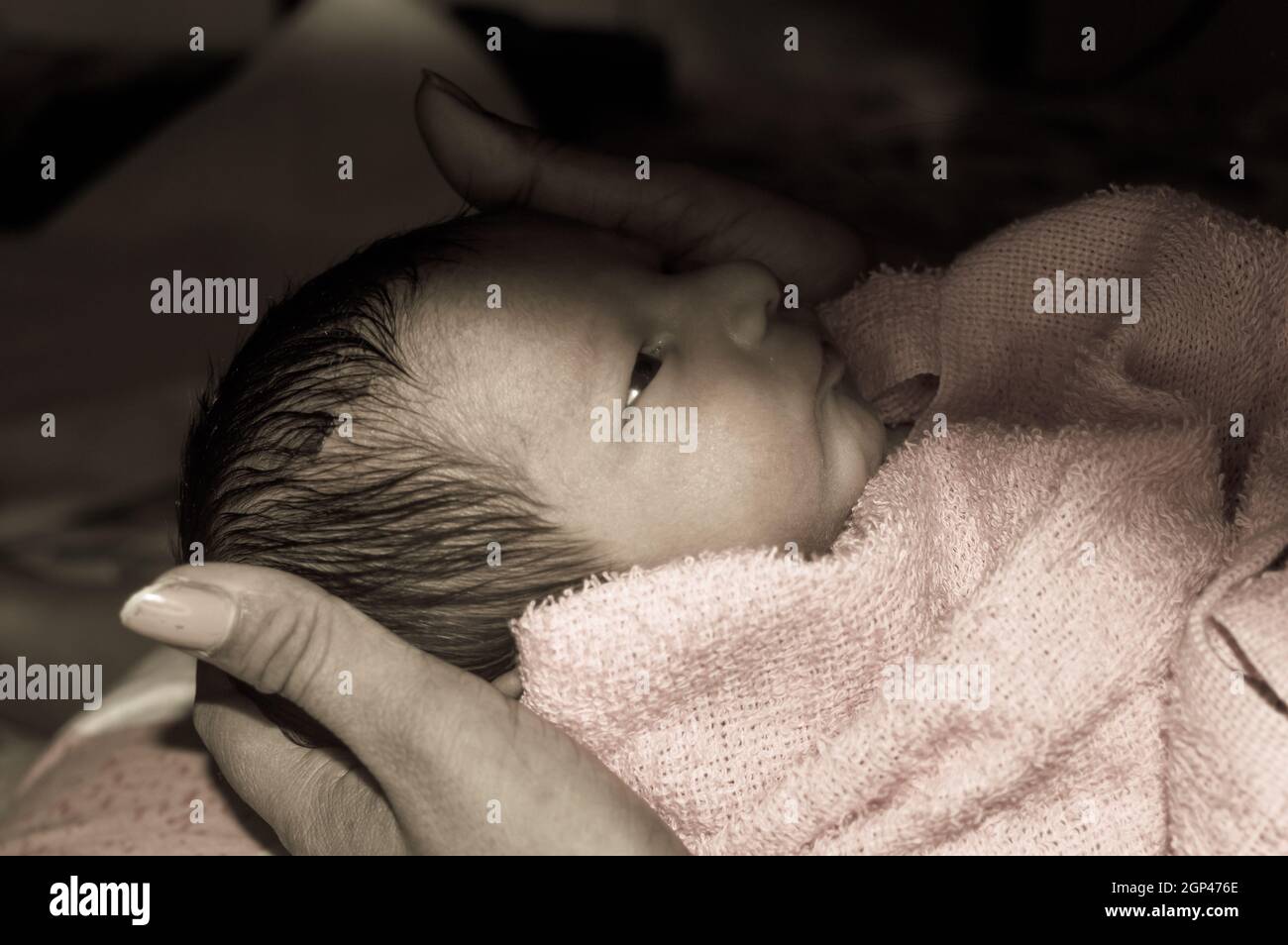 Hermoso recién nacido niño closeup (6 días de edad) acostado en el regazo  de la madre en el hospital prenatal. Niño envuelto en manta para bebé (ropa  de abrigo) sonriendo y mira
