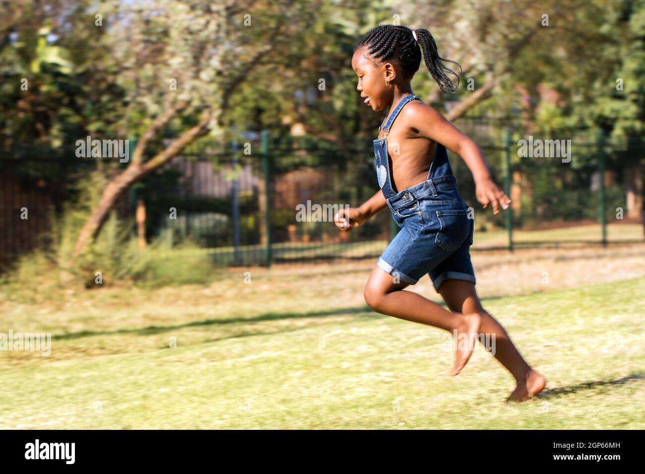 Primer plano retrato de acción de un niño africano corriendo en el parque. Vista lateral de la niña de cola pequeña en movimiento. Foto de stock