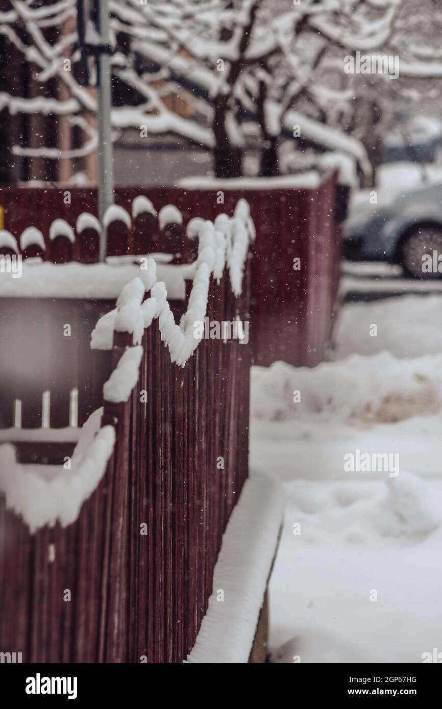 Valla de madera pintada de rojo durante el invierno nieve fuerte en Rumania Foto de stock