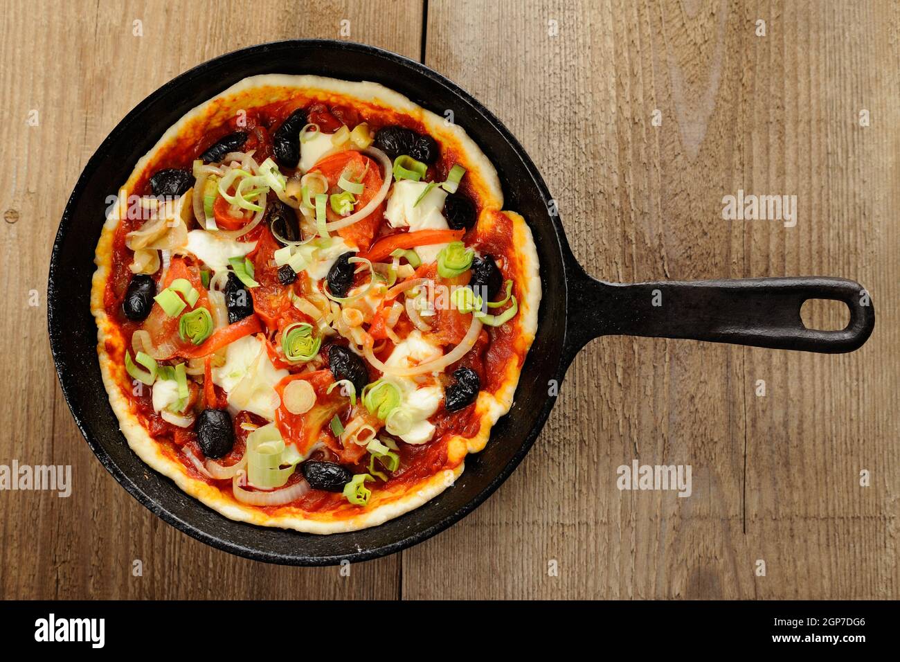 Pizza cruda con aceitunas y salmón en sartén de hierro fundido sobre mesa  de madera Fotografía de stock - Alamy