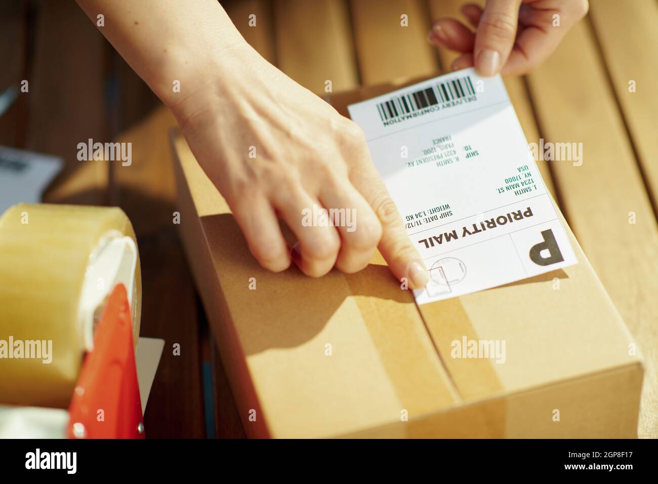 Negocio de entrega. Primer plano de la hembra en el almacén aplicando la  etiqueta de envío al paquete Fotografía de stock - Alamy