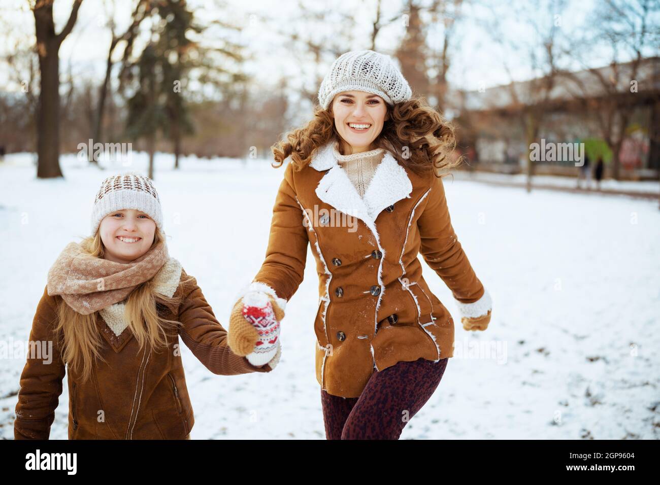 feliz madre e hija con estilo en un sombrero de punto y abrigos de piel de  oveja con manoplas en un sombrero de punto y abrigo de piel de oveja fuera  en
