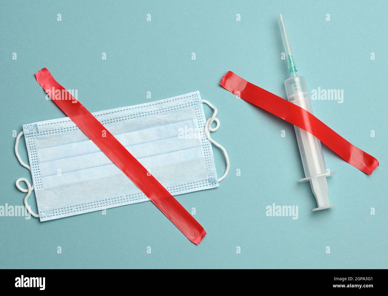 jeringa médica de plástico con cinta roja, fondo azul. Negativa a vacunar Foto de stock