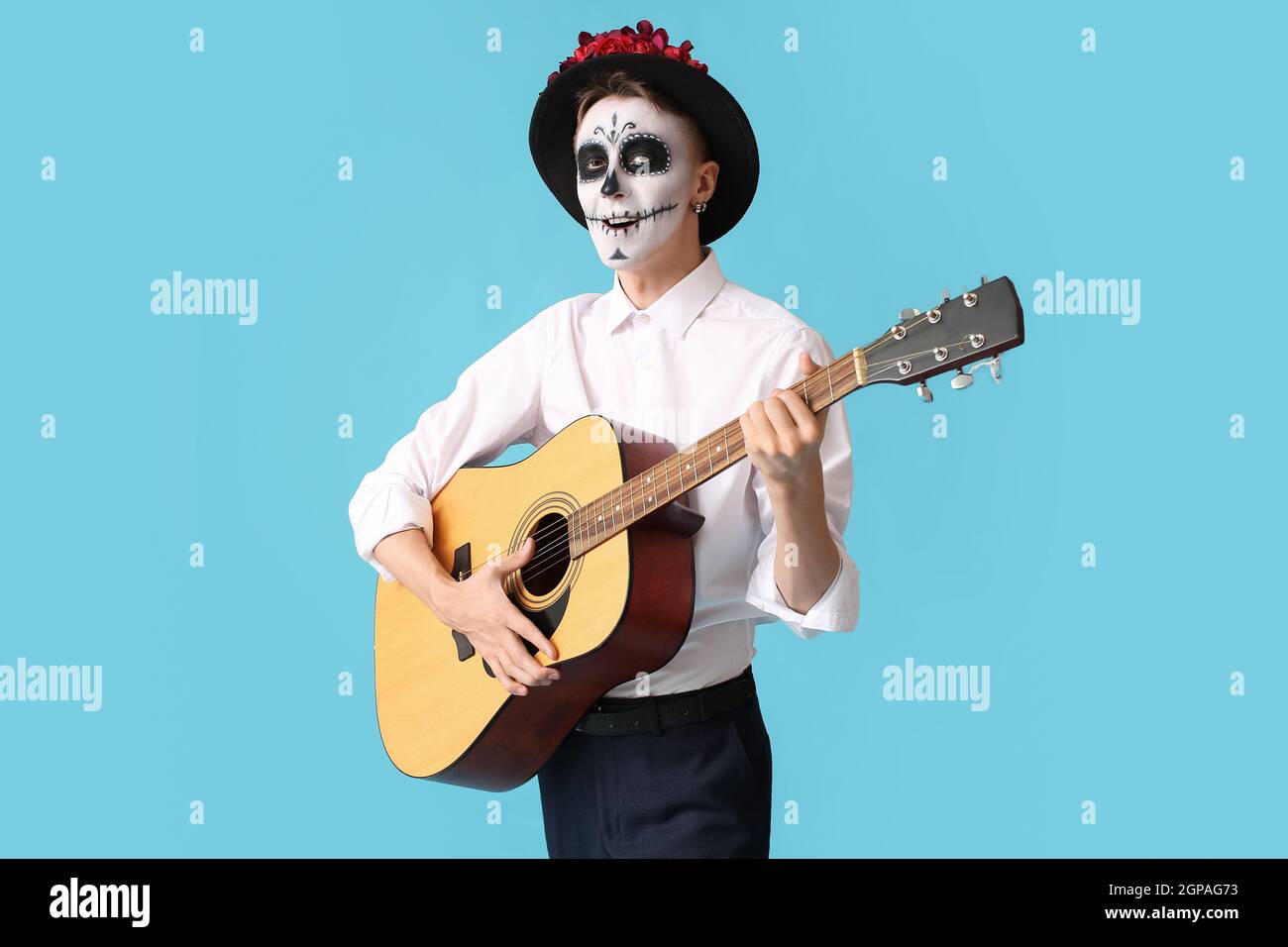 Joven con cráneo pintado en su cara y guitarra contra fondo de color.  Celebración del Día de los Muertos de México (El Dia de Muertos Fotografía  de stock - Alamy