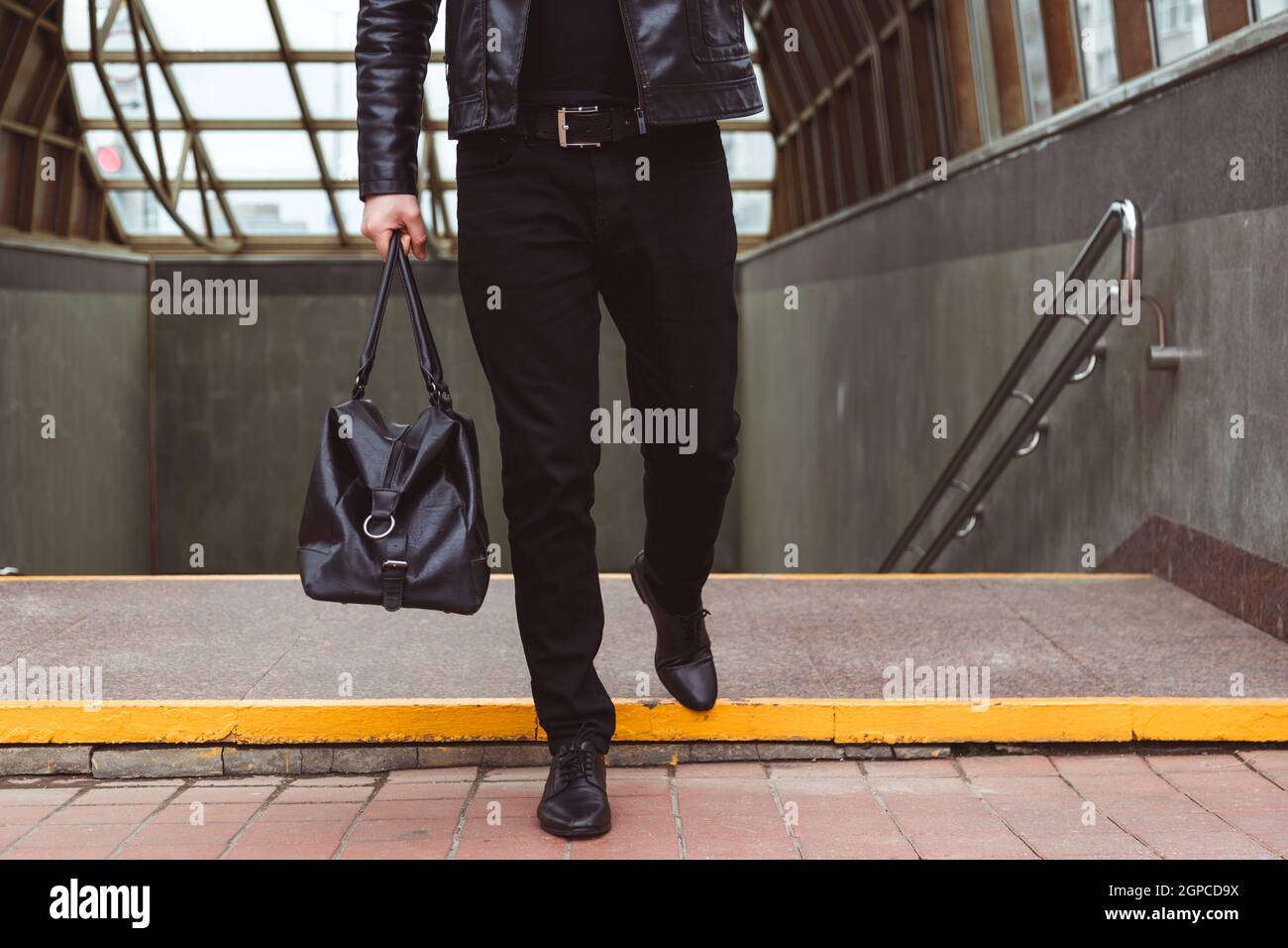 Hombre vestido de moda camina desde el cruce subterráneo con bolsa de  cuero. Estilo urbano informal Fotografía de stock - Alamy