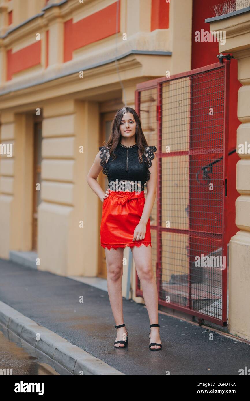 Mujer posando en la calle en falda de cuero rojo y una elegante negra Fotografía de stock -