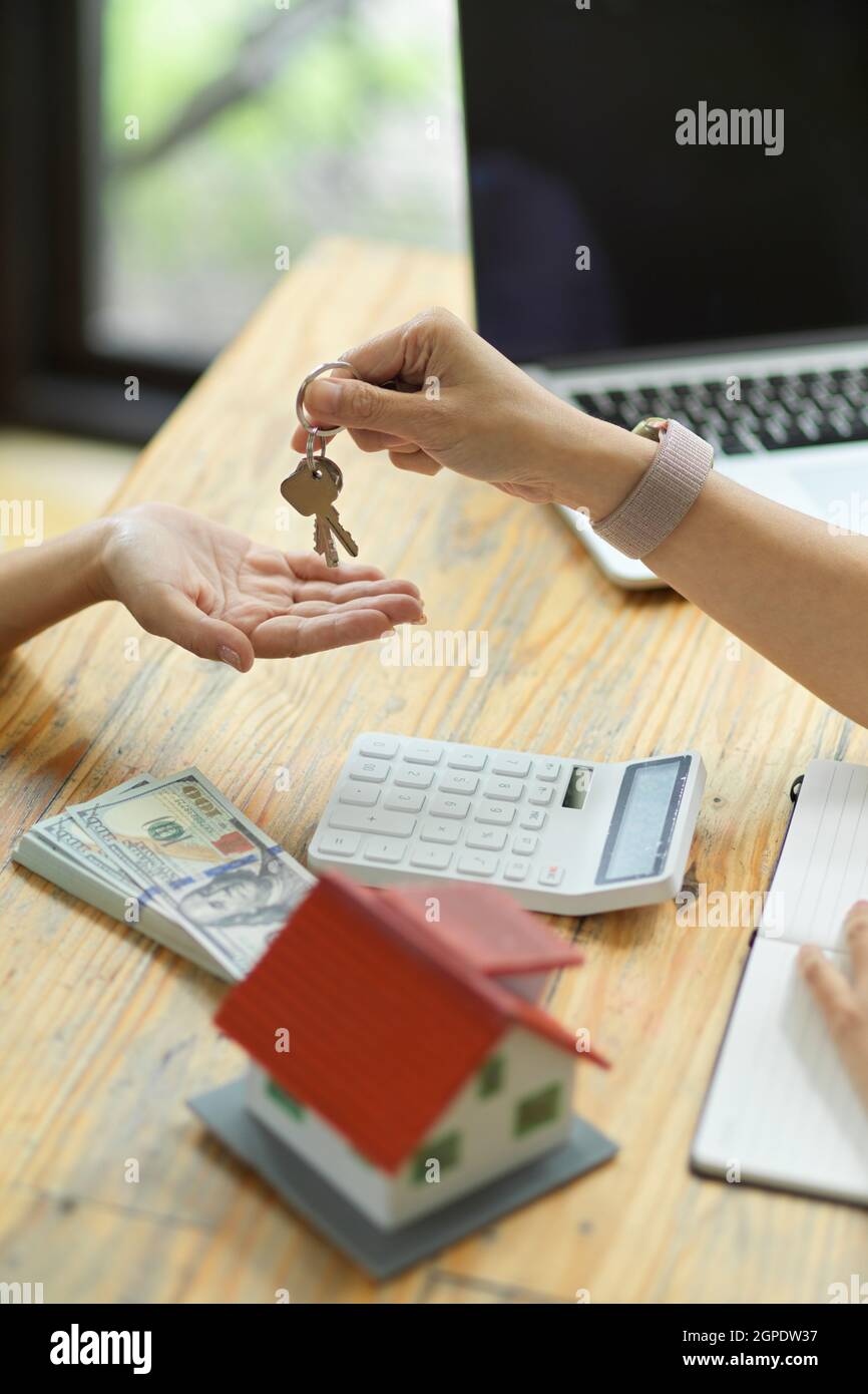 agente inmobiliario residente femenino que da las llaves de una casa al nuevo dueño después de firmar contrato y pagar el depósito de la casa Foto de stock