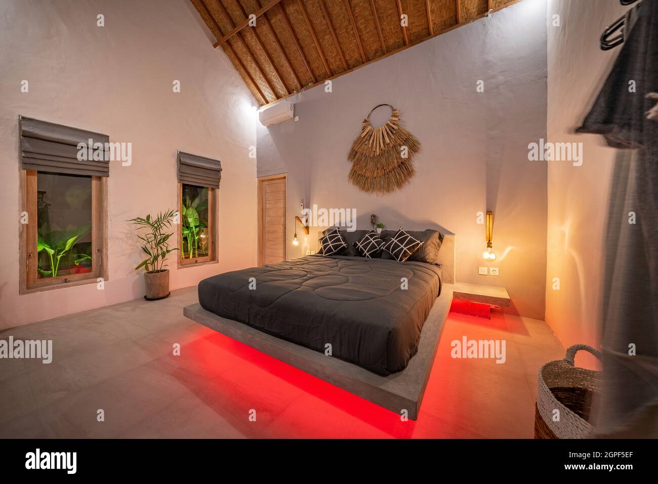 Sureste Plaga Descubrimiento moderna cama de pino de piedra con iluminación led roja, lámparas de pared.  Dormitorio en apartamento loft de lujo - fotografiado con poca luz para  resaltar la atmósfera de luz roja Fotografía