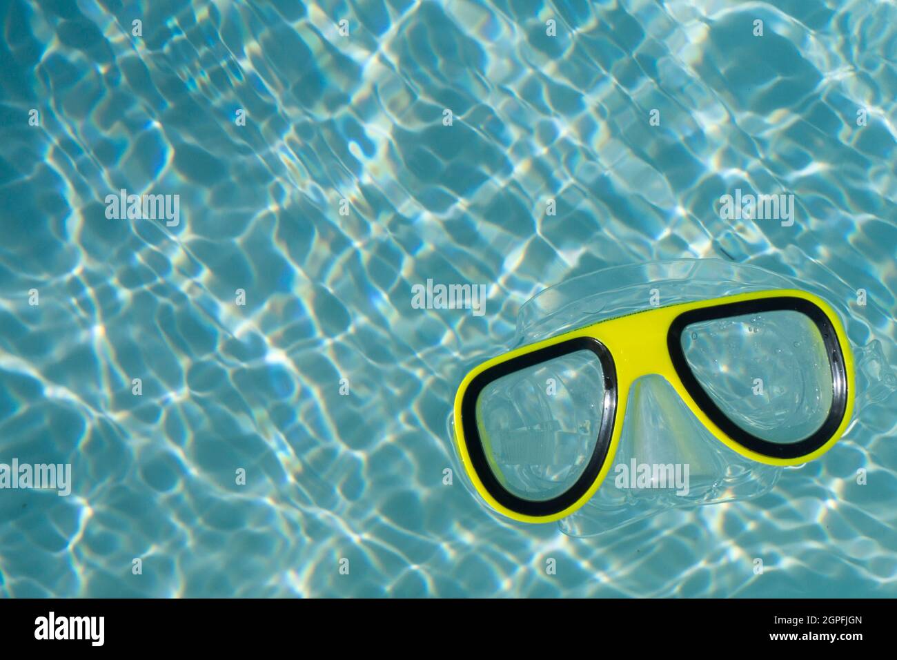 Unas gafas amarillas de buceo flotando en una piscina azul claro ondulada  Fotografía de stock - Alamy