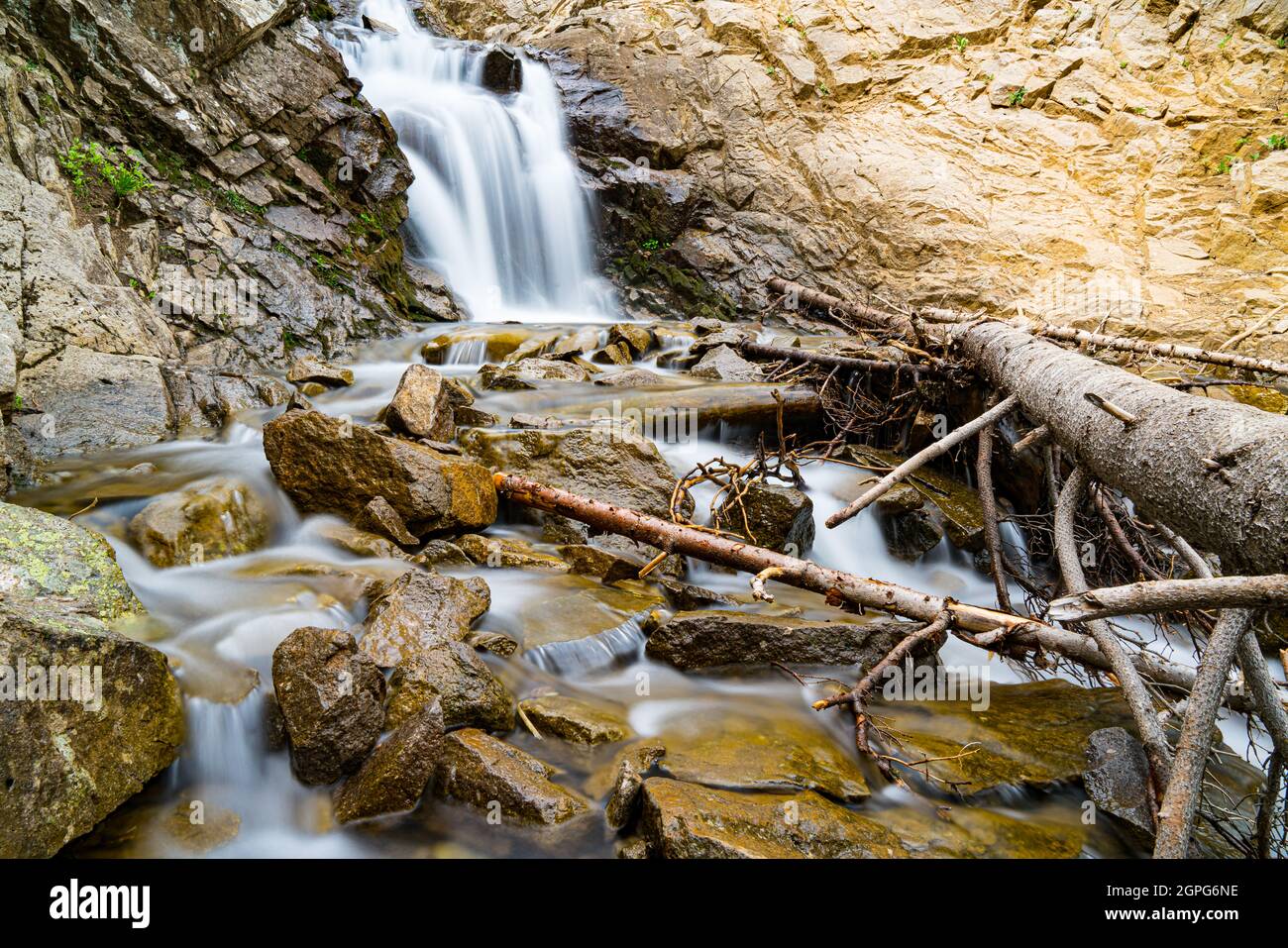 Larga exposición de una hermosa cascada a lo largo de un alto arroyo de montaña Foto de stock