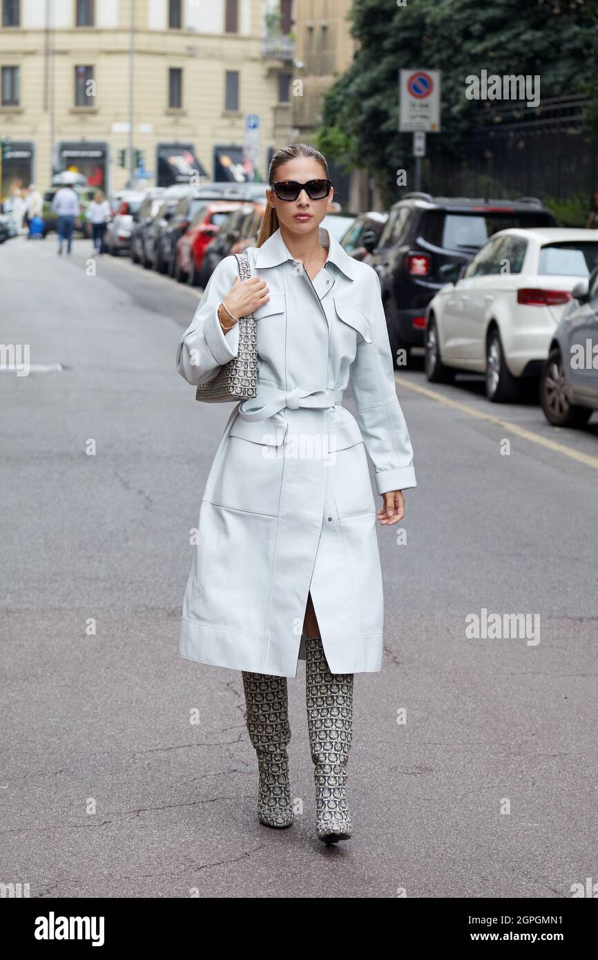 MILÁN, ITALIA - 25 DE SEPTIEMBRE de 2021: Mujer con abrigo de trinchera  gris pálido y botas con patrón de monograma Ferragamo y bolsa antes de  Salvatore Ferragamo moda sh Fotografía de stock - Alamy