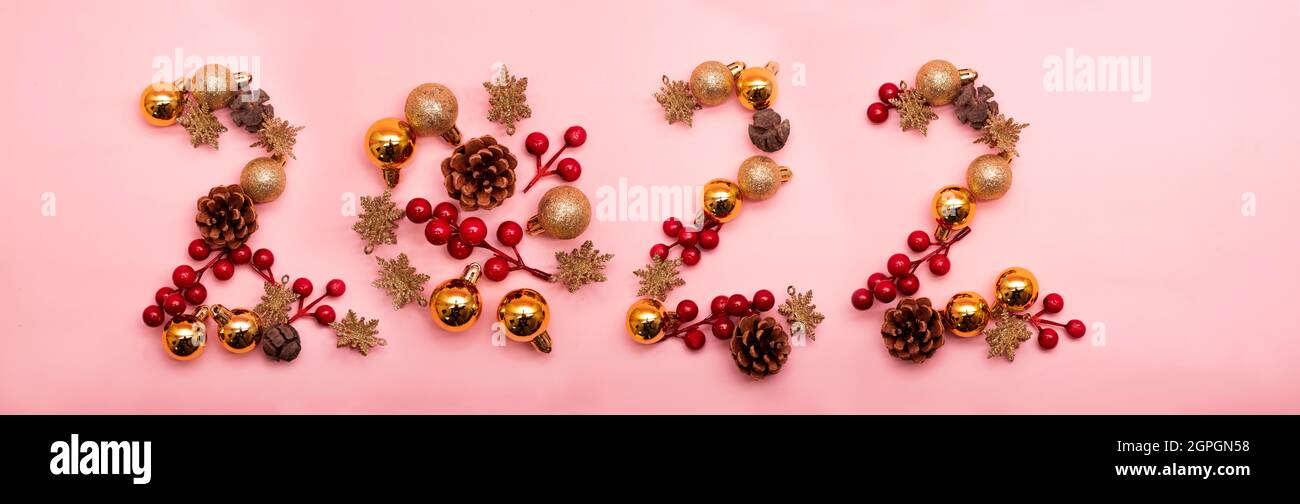 Número 2022 escrito con adornos de Navidad sobre fondo rosa Foto de stock