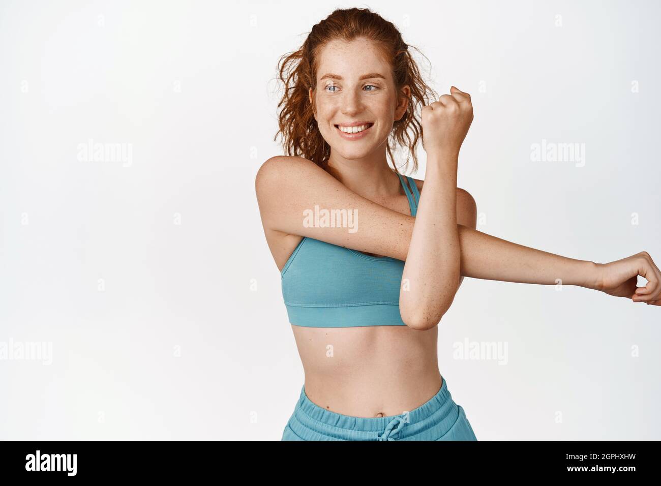 Sonriente pelirroja chica haciendo ejercicios de fitness, estirando los  brazos para calentar antes del entrenamiento, de pie en activo sobre fondo  blanco FotografÃ­a de stock - Alamy