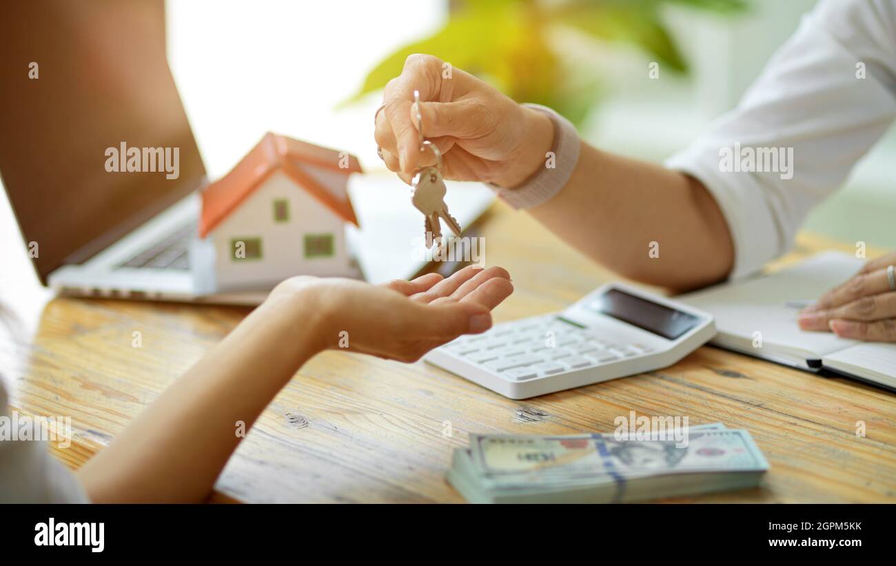 Agente inmobiliario que da una llave de la casa al nuevo comprador después de firmar la compra de contratc y el depósito pagado de la casa Foto de stock