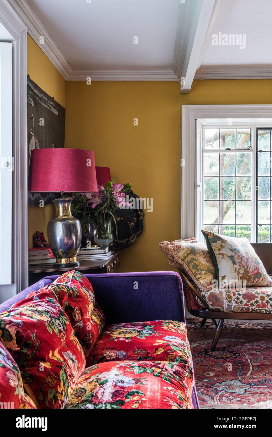 Sofá cama ercol con una mezcla de colores llamativos y telas en la sala de estar Suffolk. Foto de stock