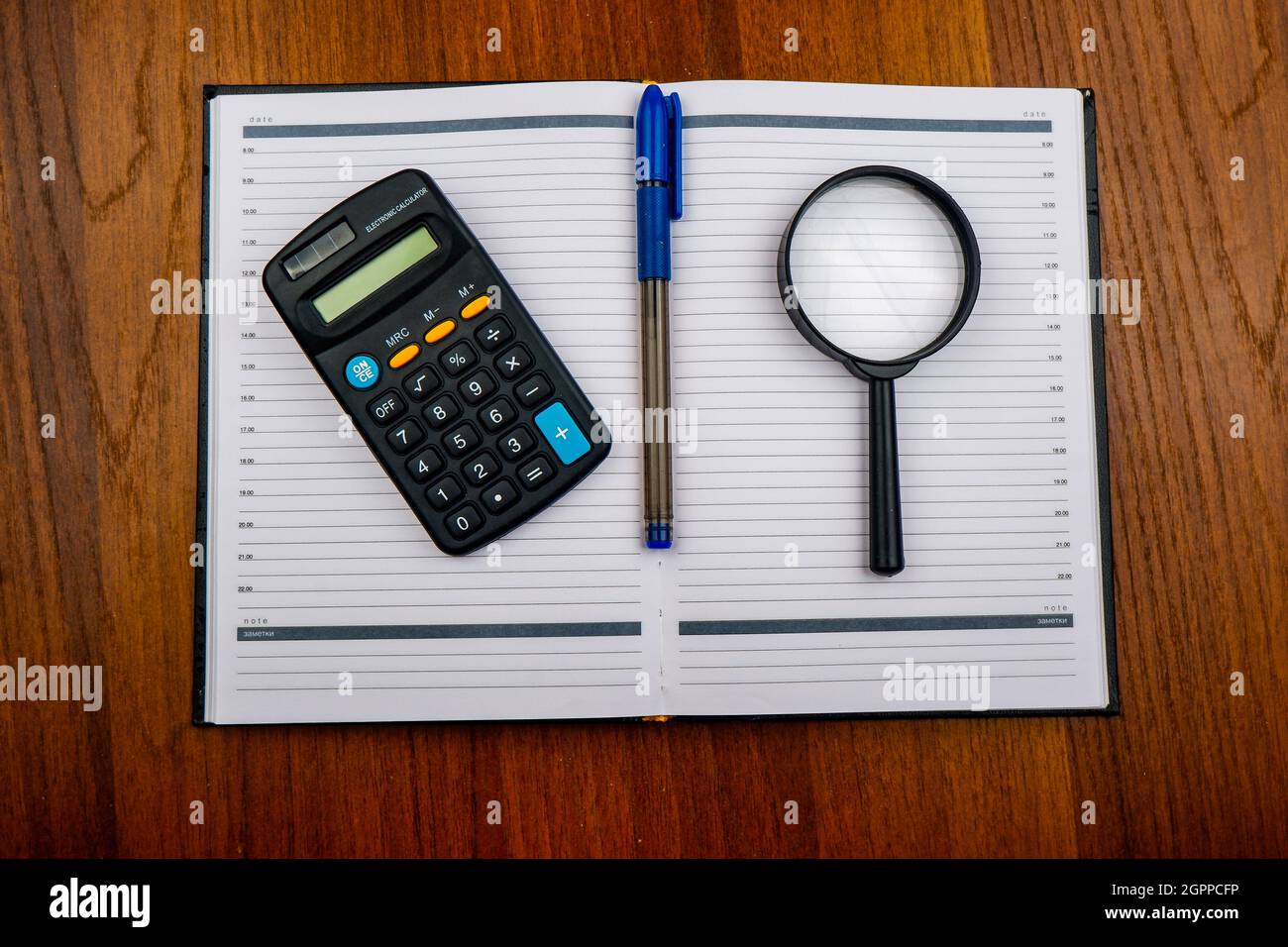 una lupa, una pluma, una calculadora y un diario están en la  tabla.financial planning.a concepto para planear los gastos mensuales  Fotografía de stock - Alamy