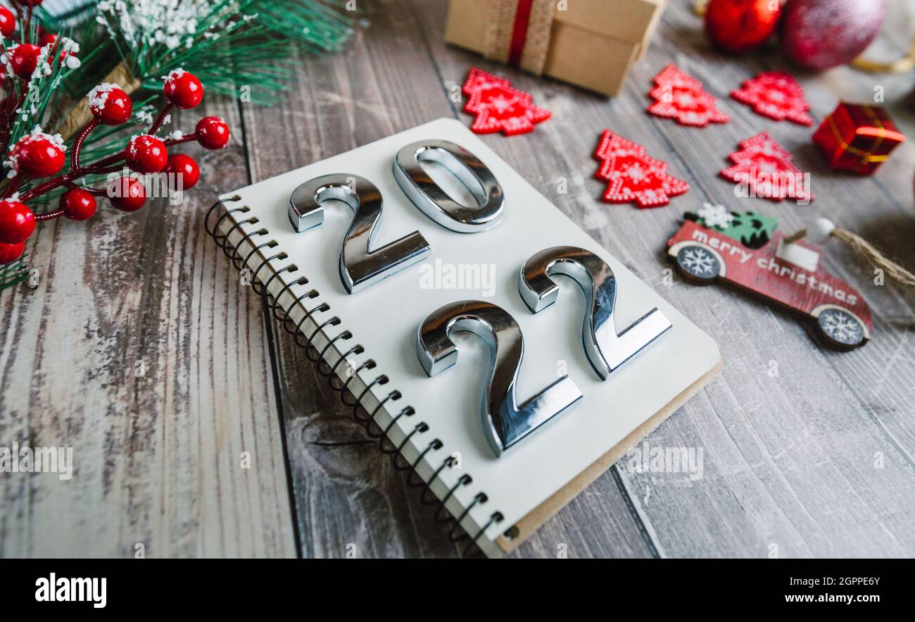 Números 2022 en un bloc de notas espiral sobre un fondo de madera con decoraciones de Navidad Foto de stock