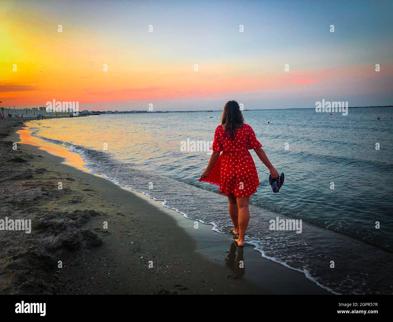 Mujer en vestido rojo Caminando sola en la playa al atardecer Fotografía de  stock - Alamy