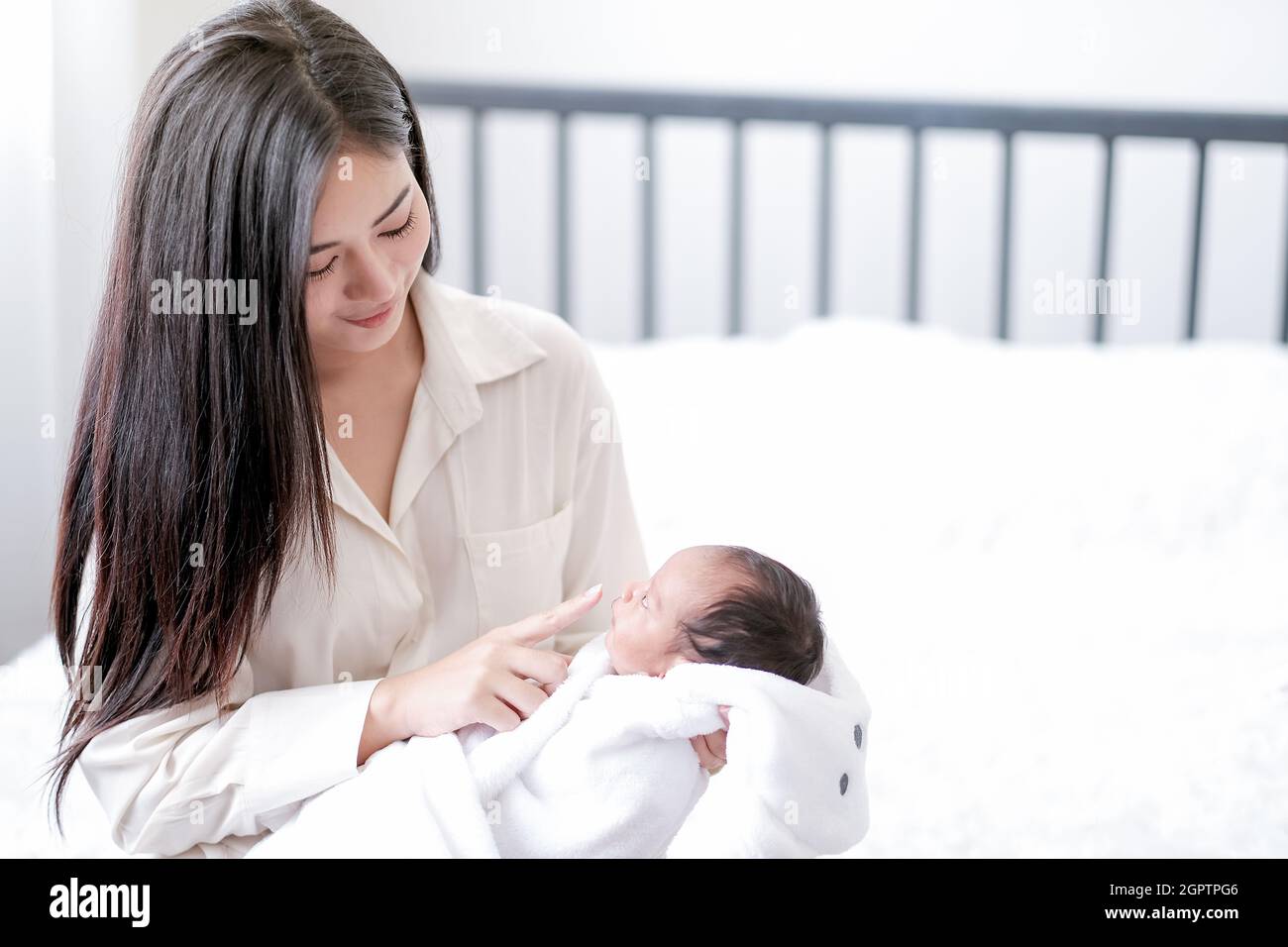Madre sonriente sosteniendo al bebé en casa Foto de stock