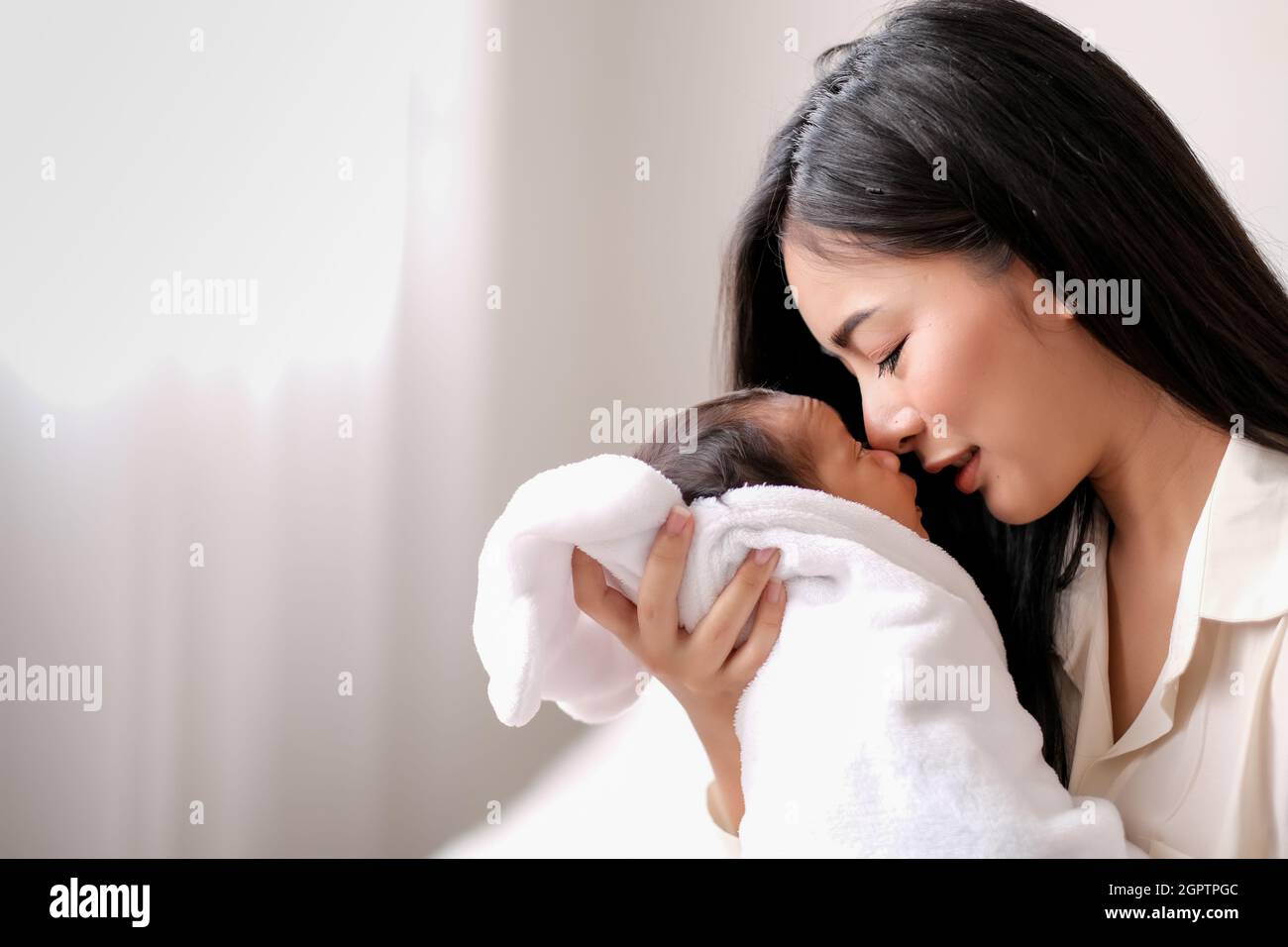 Madre sonriente sosteniendo al bebé en casa Foto de stock
