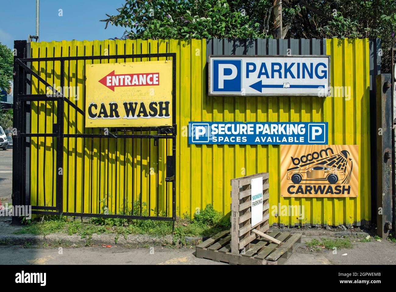 Entrada al lavado de coches detrás de una valla amarilla pintada de colores brillantes, estacionamiento seguro disponible, Holloway, el barrio londinense de Islington Foto de stock