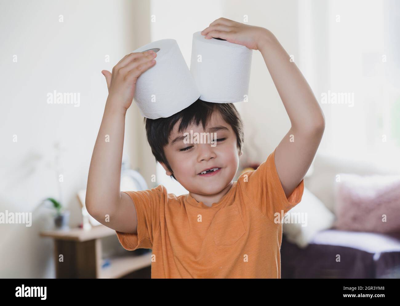 Lindo niño sosteniendo rollo de papel higiénico en la cabeza en casa  Fotografía de stock - Alamy