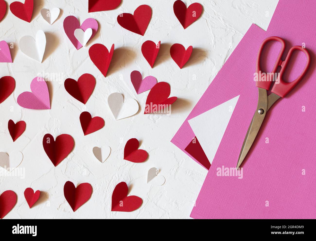 Corazones de papel rojos, blancos y rosas cortados en papel. Decoración  para el día de San Valentín en una mesa blanca Fotografía de stock - Alamy