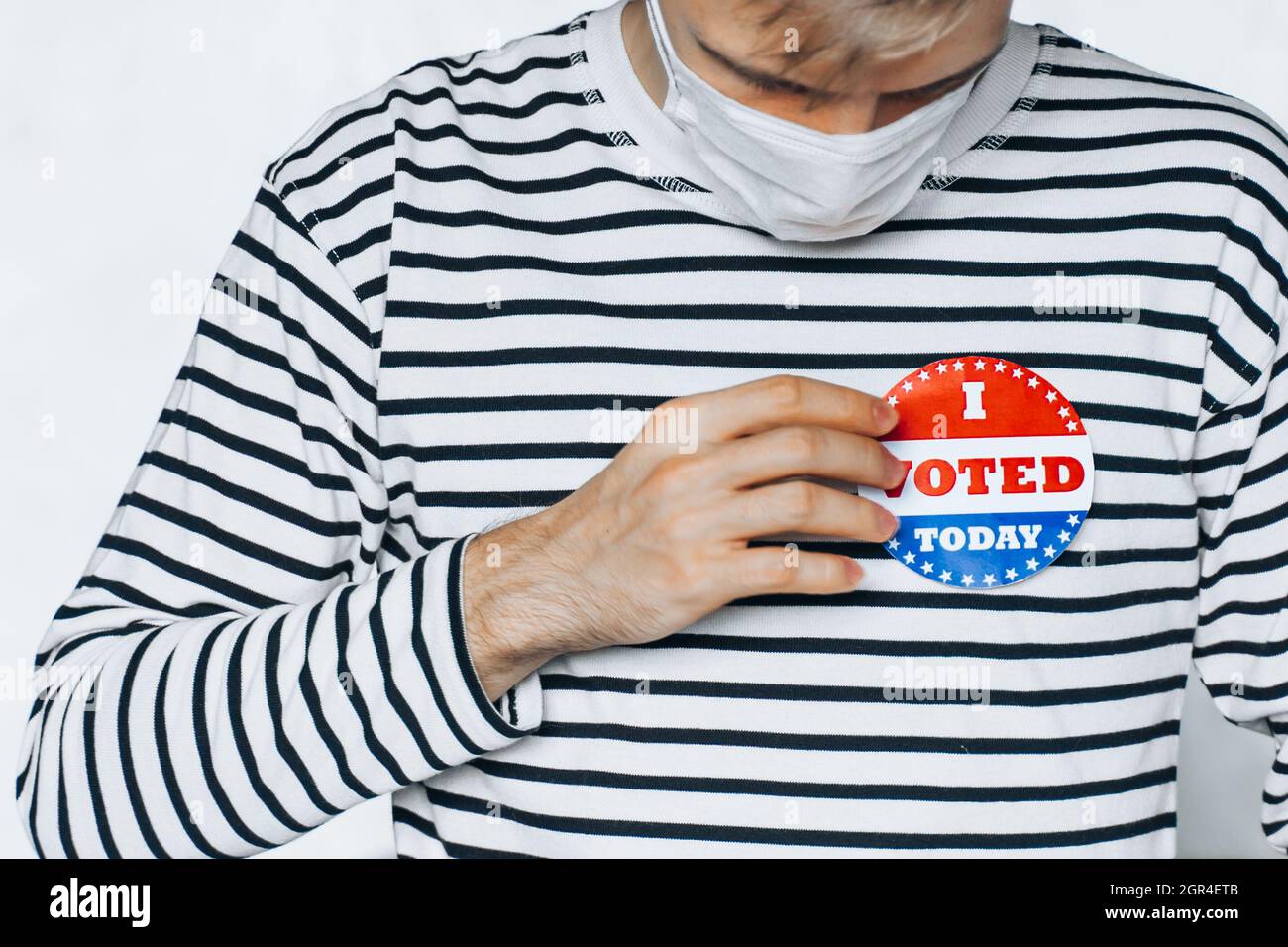 PIN de la máscara de hombre votado. Día de las Elecciones Coronavirus Pandemic Estados Unidos Aisló Blanco Nuevo Normal Foto de stock