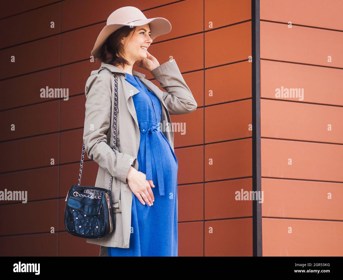 Caminando Chic Embarazada Brunette en ropa moderna moda. Abrigo beige, sombrero elegante, vestido Fotografía de stock Alamy