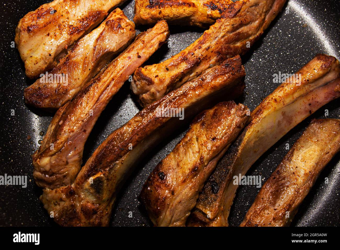 Costillas de cerdo fritas en una sartén antiadherente. Primer plano  Fotografía de stock - Alamy