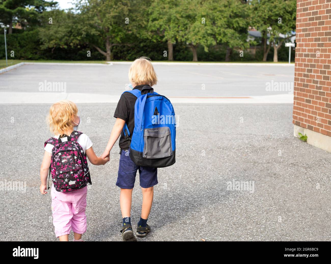 Niños en máscaras van a la escuela y al de infantes, mano, usando mochilas Fotografía de stock - Alamy