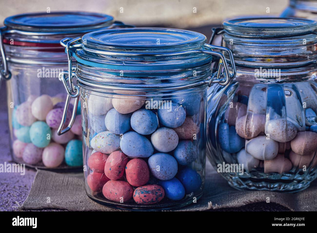 Jarras de vidrio llenas de caramelos de Pascua, color pastel, Mini huevos de caramelo y judías verdes Foto de stock