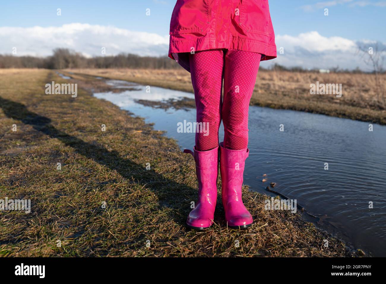 Chica joven con botas de agua rosadas de pie cerca De un charco de barro en  primavera Fotografía de stock - Alamy