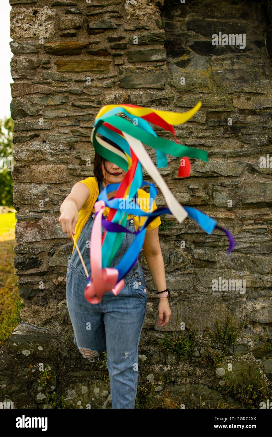 Longitud completa de una mujer ondeando con cintas arcoíris. Foto de stock