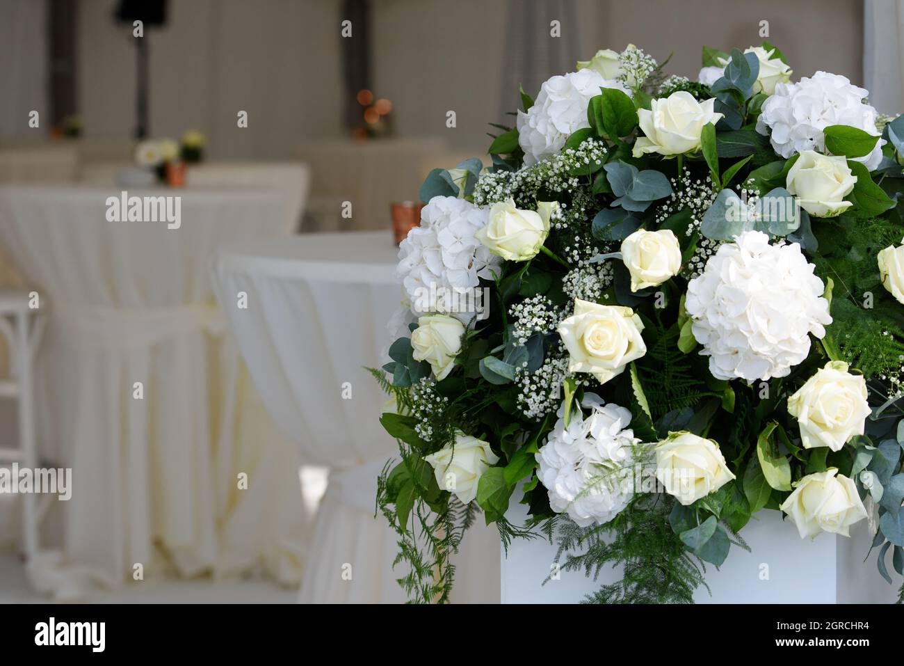 Rosas blancas en arreglos florales para una recepción con mesas defocadas  con servilletas blancas Fotografía de stock - Alamy