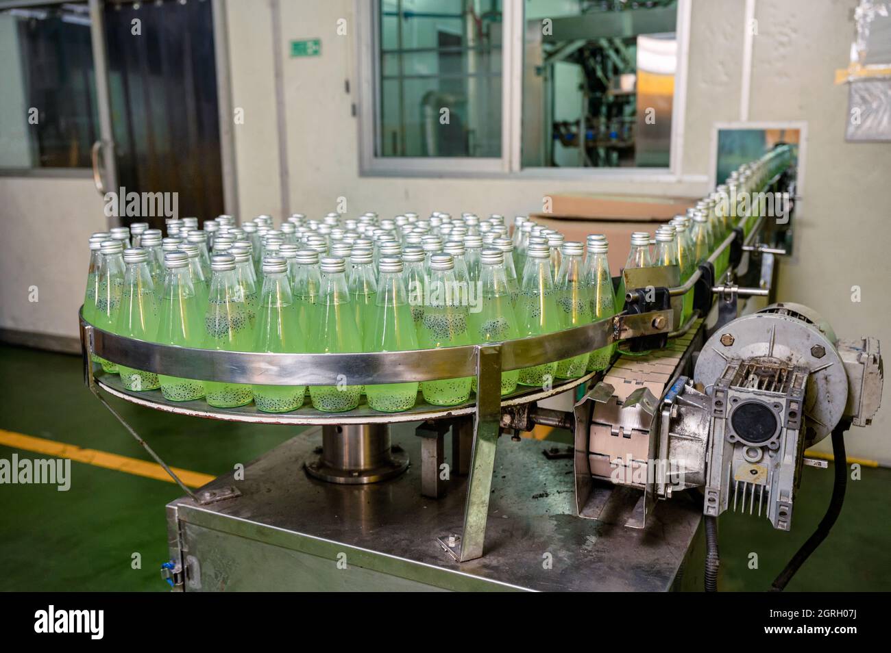 Producto de jugo verde embotellado en cinta transportadora con máquina automática en fábrica de procesamiento de bebidas Foto de stock