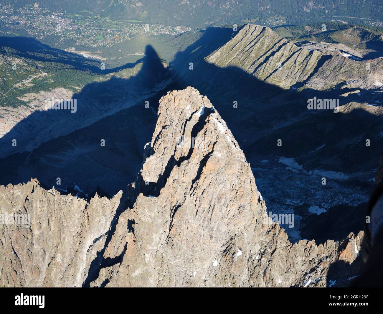 VISTA AÉREA. Cara sureste de Les Drus (3754 metros de altura) con su sombra que se proyecta sobre el Valle de Chamonix (1100 metros). Alta Saboya, Francia. Foto de stock