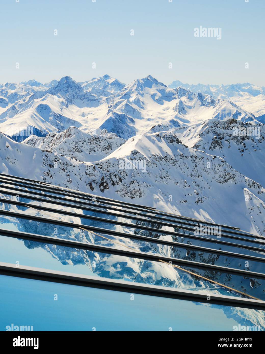 Capas de picos montañosos reflejados en el cristal - vista desde la estación de cable superior de Parpaner Rothorn en la localidad de Arosa Lenzerheide, Suiza. Vertical. Foto de stock
