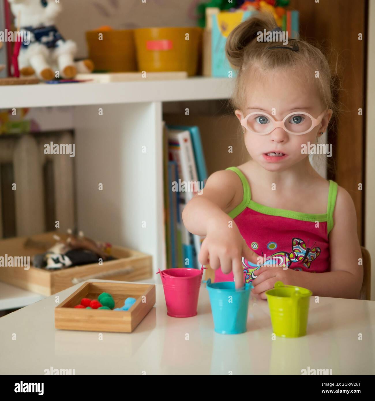 La niña con síndrome de Down desarrolla habilidades motoras finas de las manos Foto de stock