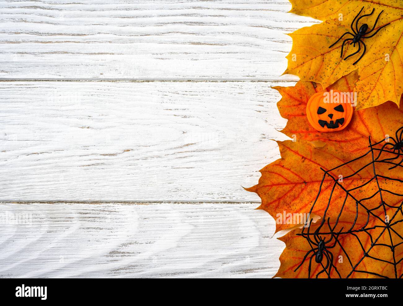 Fondo de Halloween con hojas de arce otoñales, vista superior. Objetos de Halloween sobre mesa de madera blanca con espacio para texto, plana. La naturaleza naranja Halloyen d Foto de stock