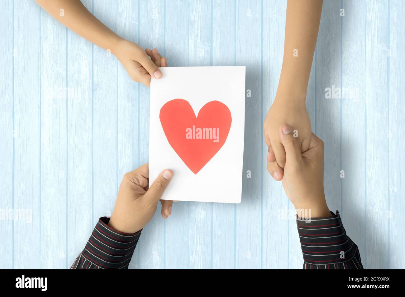 Mano recortada para dar una tarjeta de felicitación con forma de corazón  mientras sujeta las manos sobre la mesa Fotografía de stock - Alamy