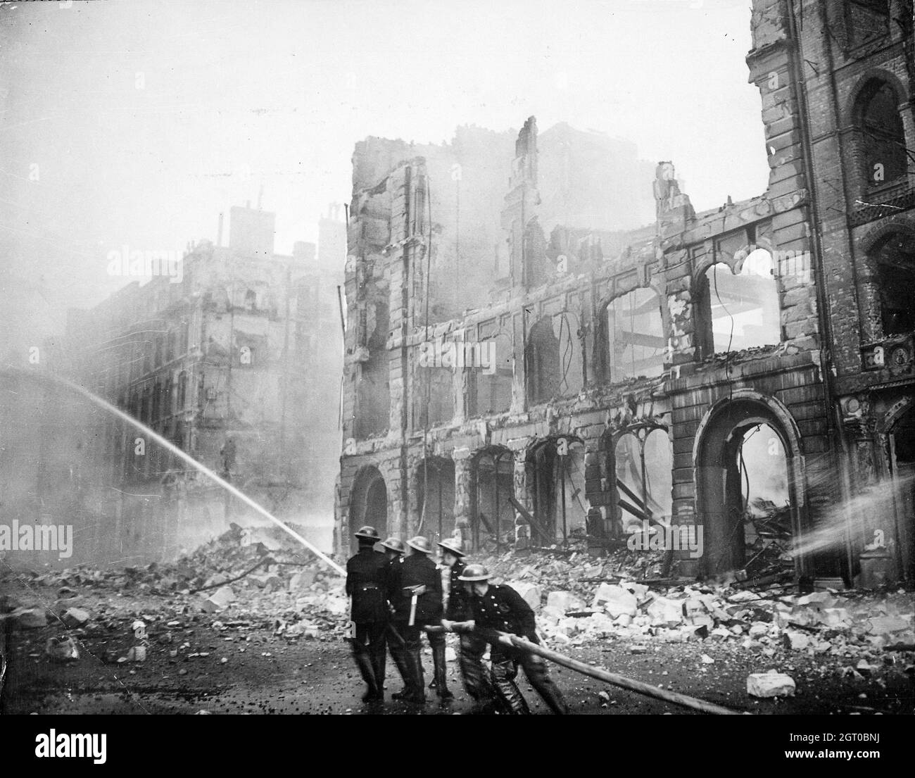 Bomberos que incendiaron en Londres después de un ataque aéreo durante el Blitz en 1941. Foto de stock