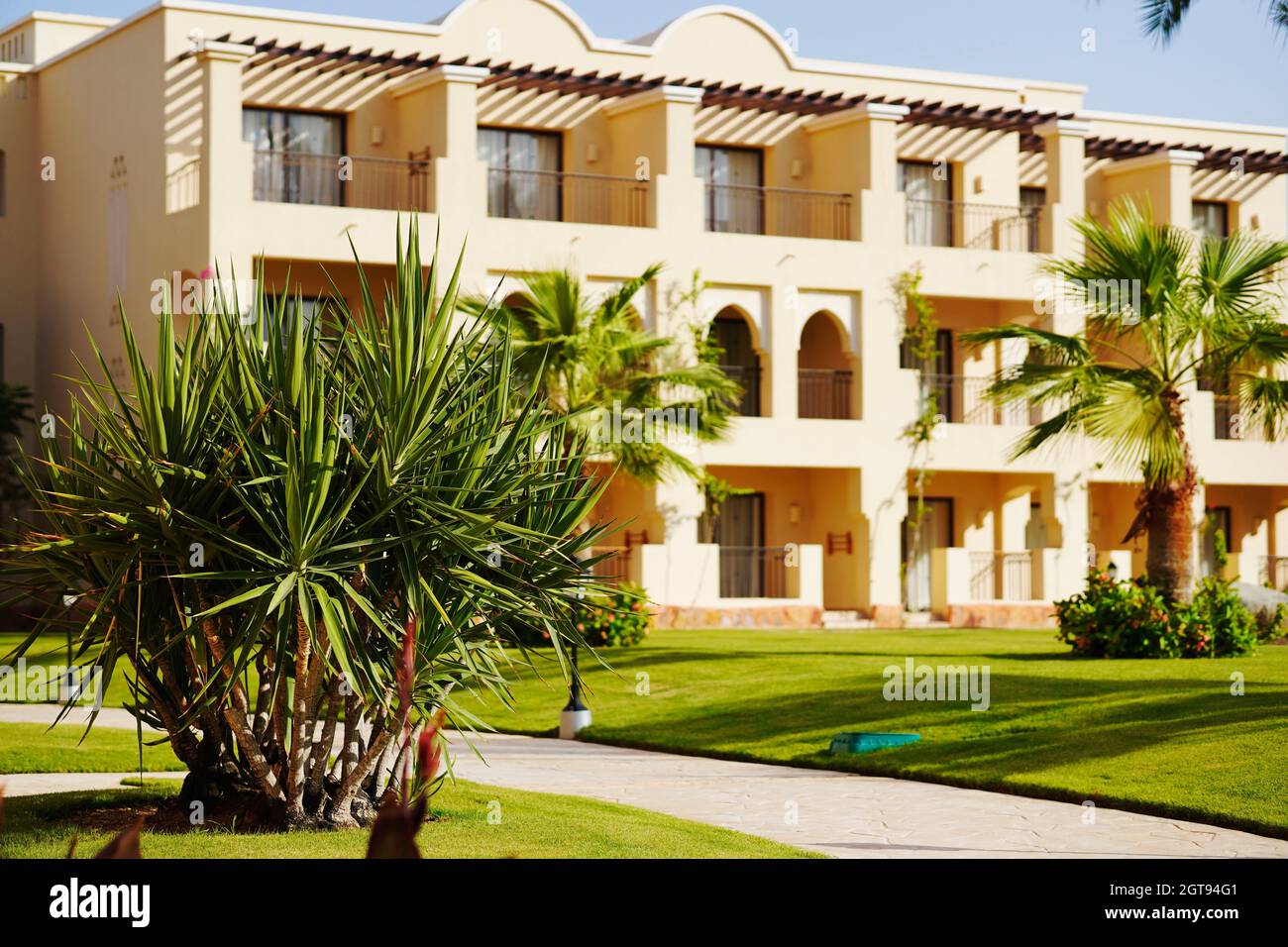 Complejo vacacional. Hotel egipcio de lujo con palmeras, césped verde perfecto y cielo azul claro. Foto de stock