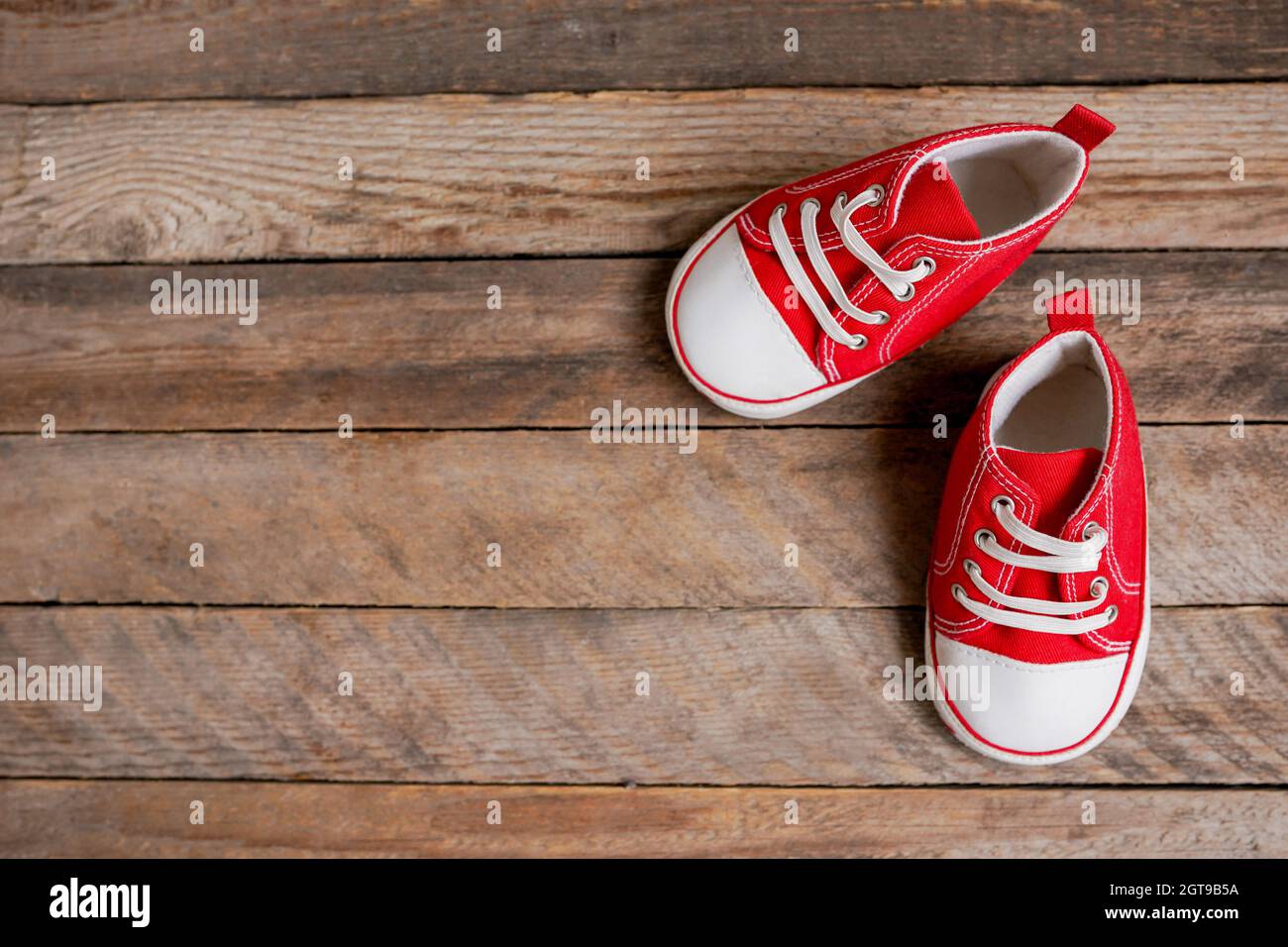 Zapatos rojos para niños pequeños sobre fondo de madera Fotografía de stock  - Alamy