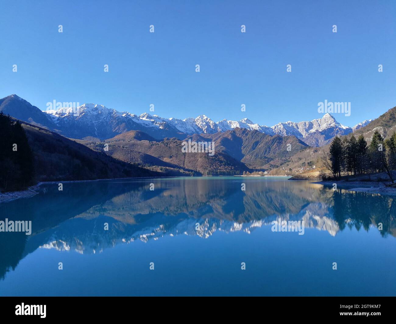Vista panorámica del lago y las montañas contra el cielo azul Foto de stock